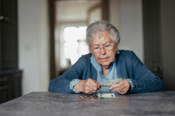 Unhappy enior woman counting her pension at home.