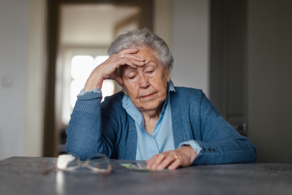 Unhappy enior woman counting her pension at home.