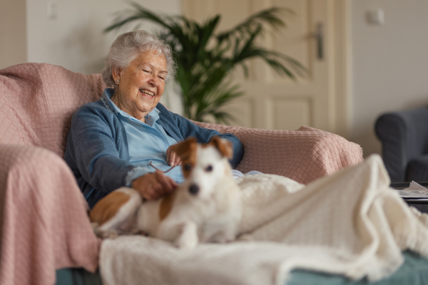 Senior woman enjoying time with her little dog at home. Dog as companion, best friends for senior.