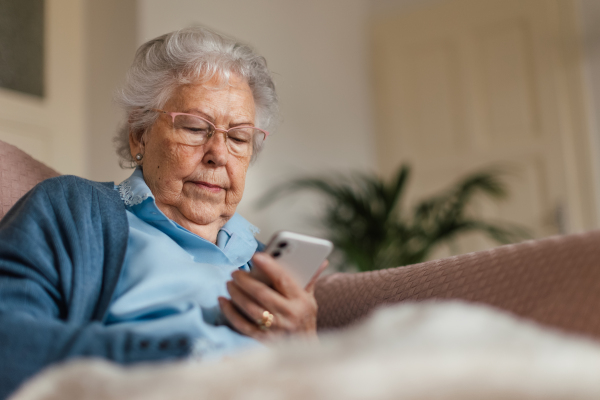 Portrait of senior woman browsing on her smartphone. Elderly woman using mobile pohone at home.