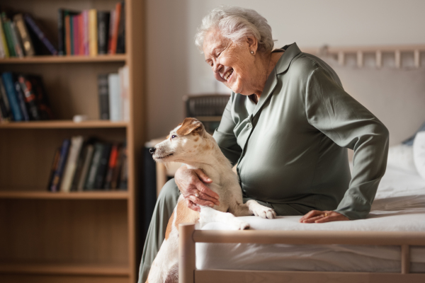 Senior woman enjoying time with her little dog at home. Dog as companion, best friends for senior.