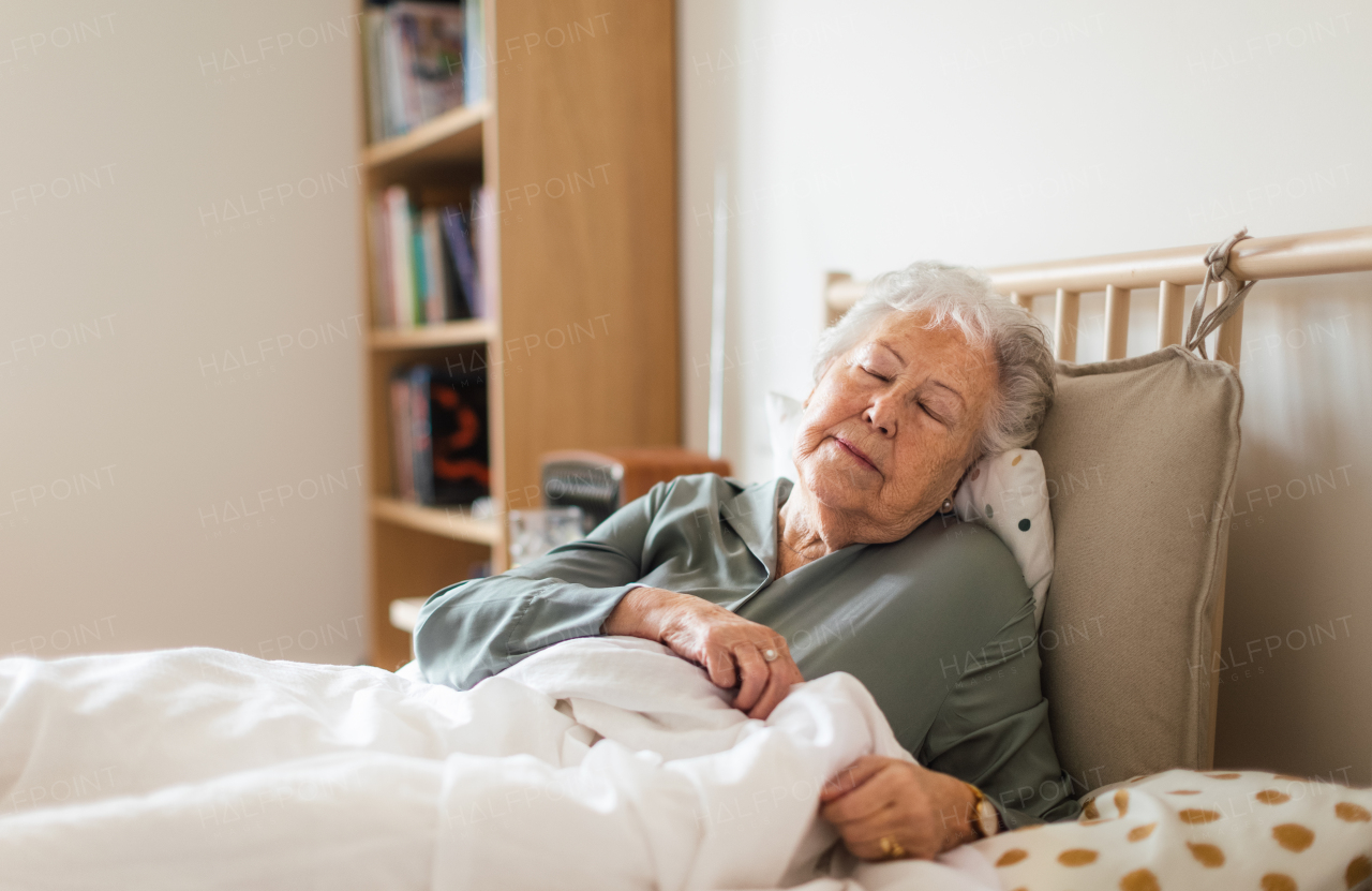 Senior woman sleeping in her bed alone. Woman having pain a feeling anxious. Loneliness and social isolation of eldery woman.