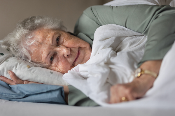 Close up of a senior woman lying on her bed and resting.