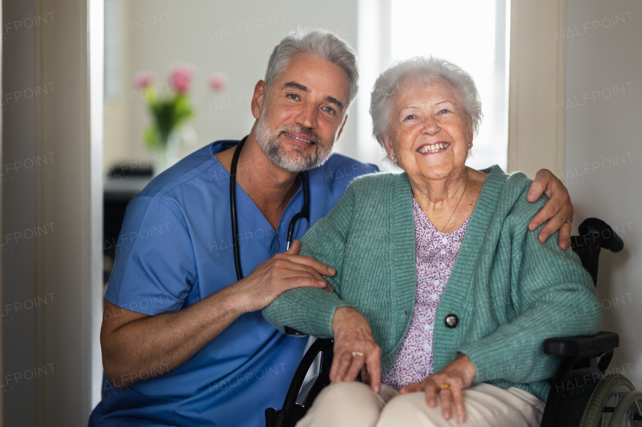 Portrait of caregiver with patient, senior woman in her home. Thoughful male nurse taking care of eldery patient on wheelchair.