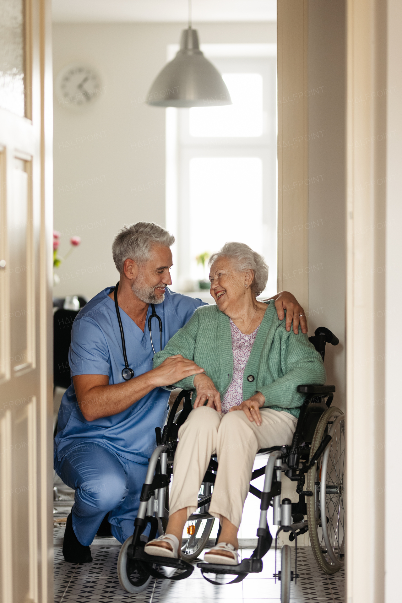 Caregiver doing regular check-up of senior client in her home. Thoughful male nurse taking care of eldery patient on wheelchair.