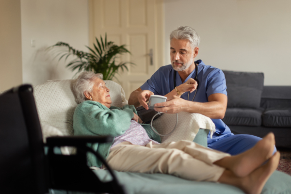 Caregiver doing regular check-up of senior client in her home.