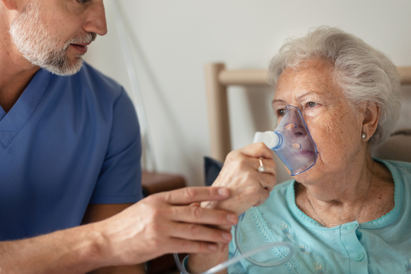 Portrait of a senior woman with inhaller, healthcare concept. Close-up of senior woman patient receiving oxygen mask.