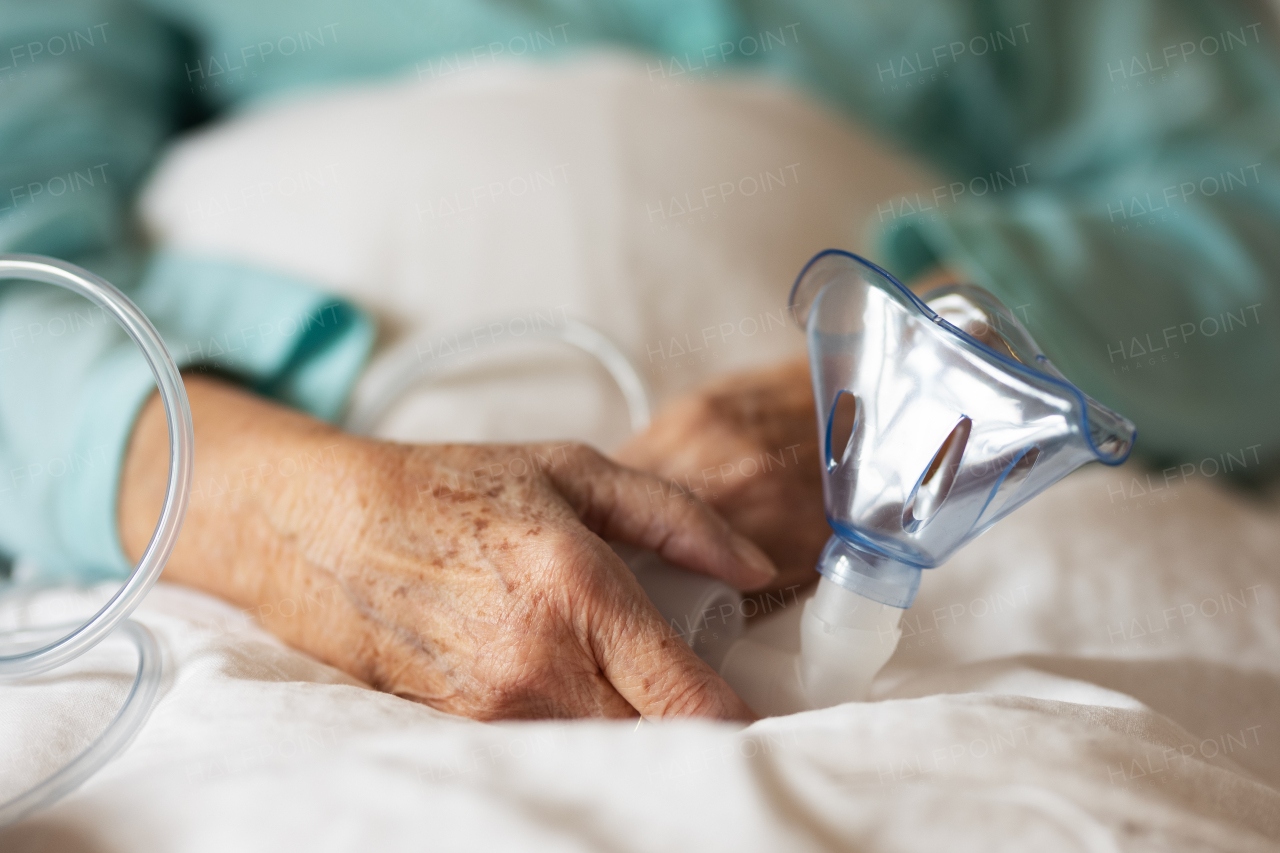 Close-up of oxygen mask holding by eldery patient in hospital. Home oxygen therapy.