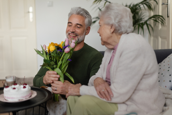 Mature man visiting his senior mother at her home.