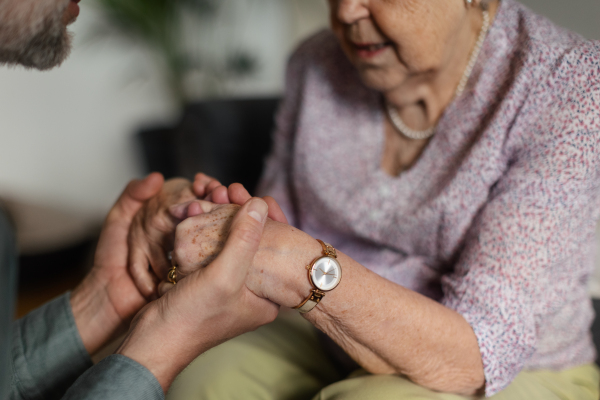 Close up of son holding hands of his senior mothe, concept of healthcare and relationships.