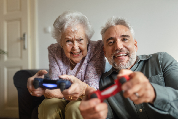 Mature man visiting his senior mother at her home, playing video games together.