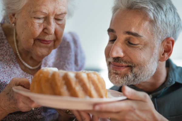 Portrait of senior mother and her adult son smelling fresh baked bundt cake.