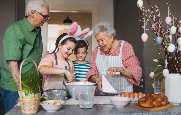 Grandparents with grandchildren preparing traditional easter meals, baking cakes and sweets. Passing down family recipes, custom and stories. Concept of family easter holidays.