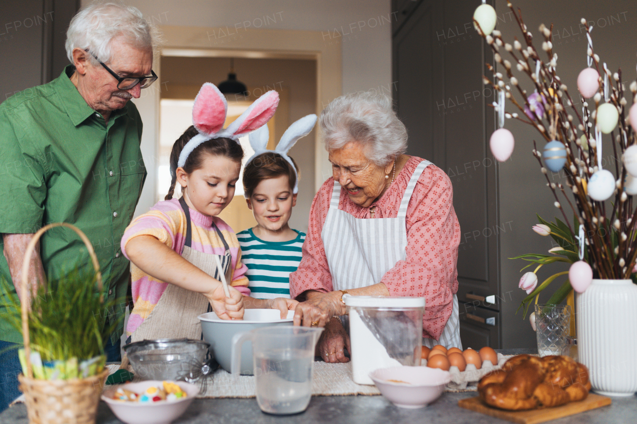 Grandparents with grandchildren preparing traditional easter meals, baking cakes and sweets. Passing down family recipes, custom and stories. Concept of family easter holidays.