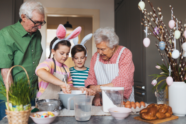 Grandparents with grandchildren preparing traditional easter meals, baking cakes and sweets. Passing down family recipes, custom and stories. Concept of family easter holidays.