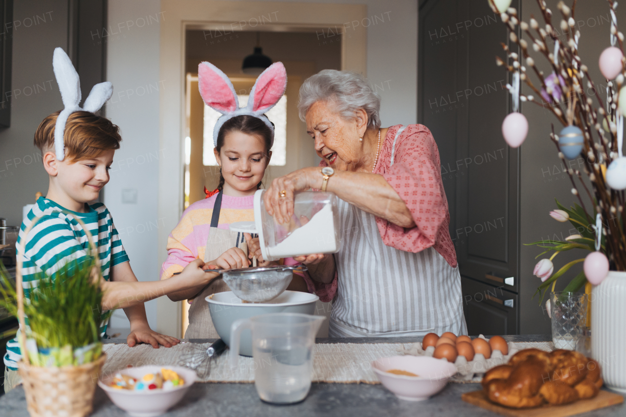 Grandmother with grandchildren preparing traditional easter meals, baking cakes and sweets. Passing down family recipes, custom and stories. Concept of family easter holidays.