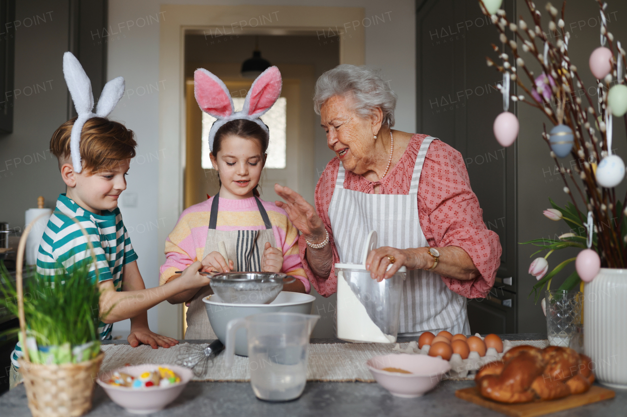 Grandmother with grandchildren preparing traditional easter meals, baking cakes and sweets. Passing down family recipes, custom and stories. Concept of family easter holidays.