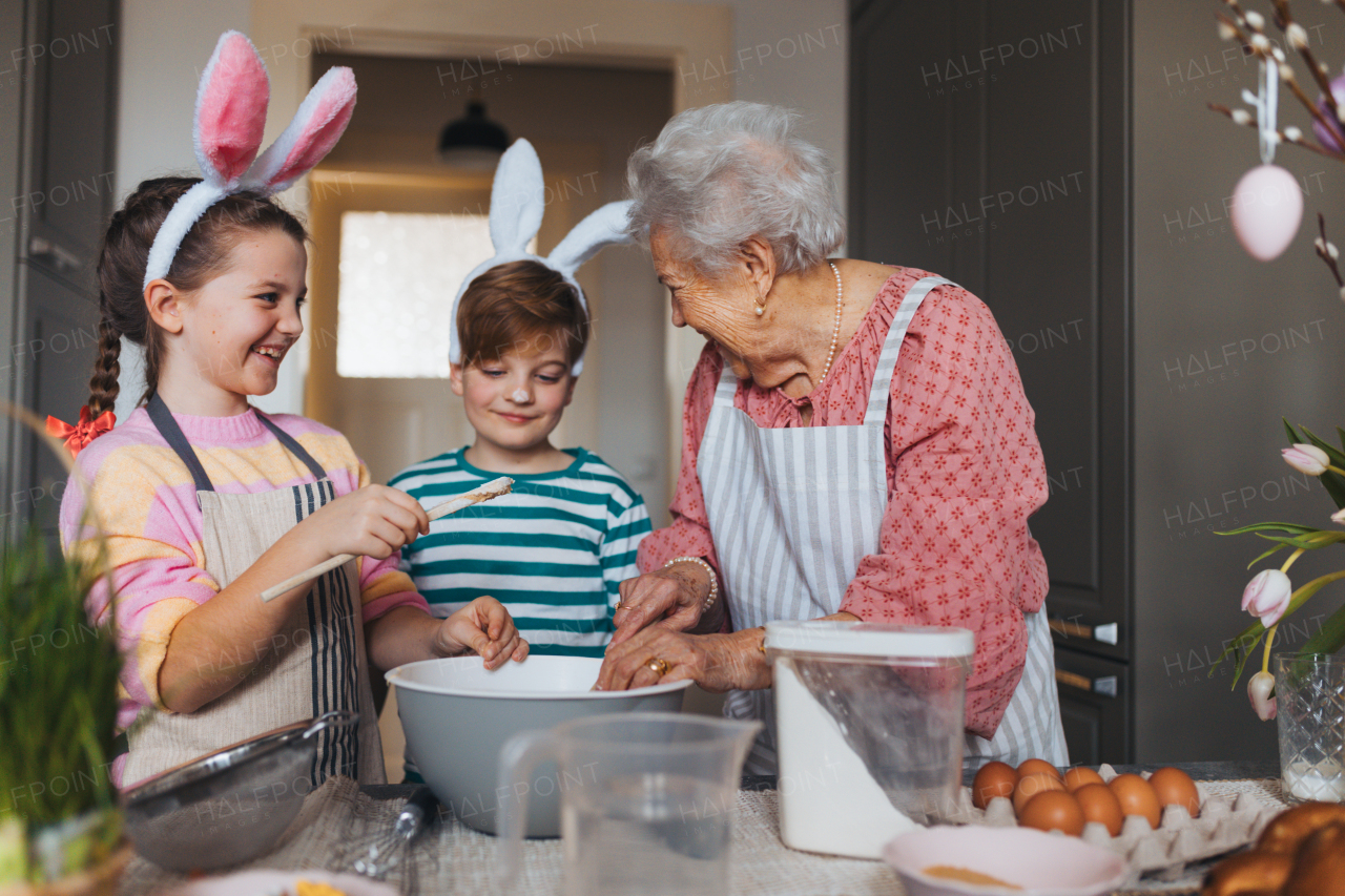 Grandmother with grandchildren preparing traditional easter meals, baking cakes and sweets. Passing down family recipes, custom and stories. Concept of family easter holidays.