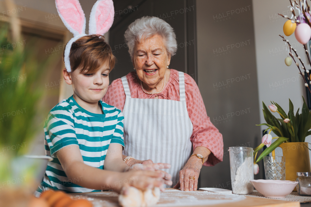 Grandmother with grandson preparing traditional easter meals, kneading dough for easter cross buns. Passing down family recipes, custom and stories. Concept of family easter holidays.