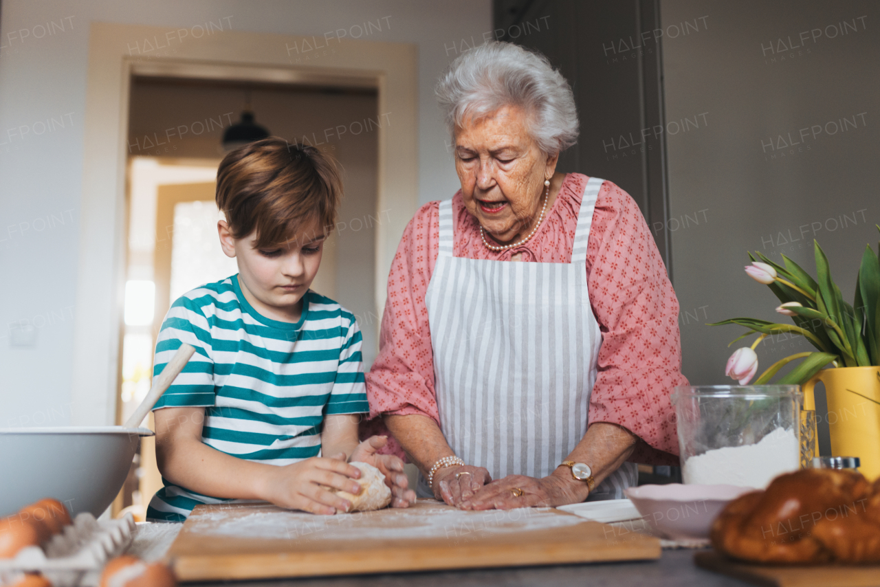 Grandmother with grandson preparing traditional easter meals, kneading dough for easter cross buns. Passing down family recipes, custom and stories. Concept of family easter holidays.