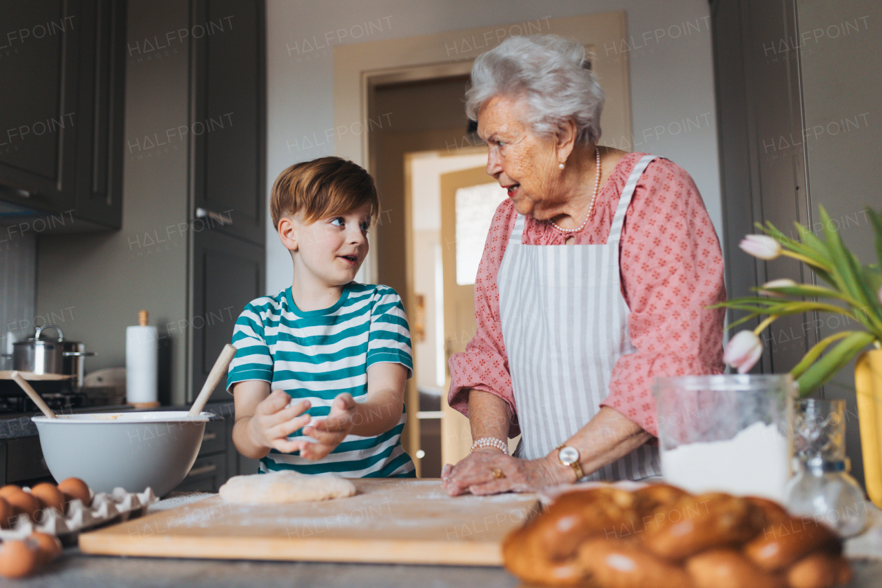 Grandmother with grandson preparing traditional easter meals, kneading dough for easter cross buns. Passing down family recipes, custom and stories. Concept of family easter holidays.