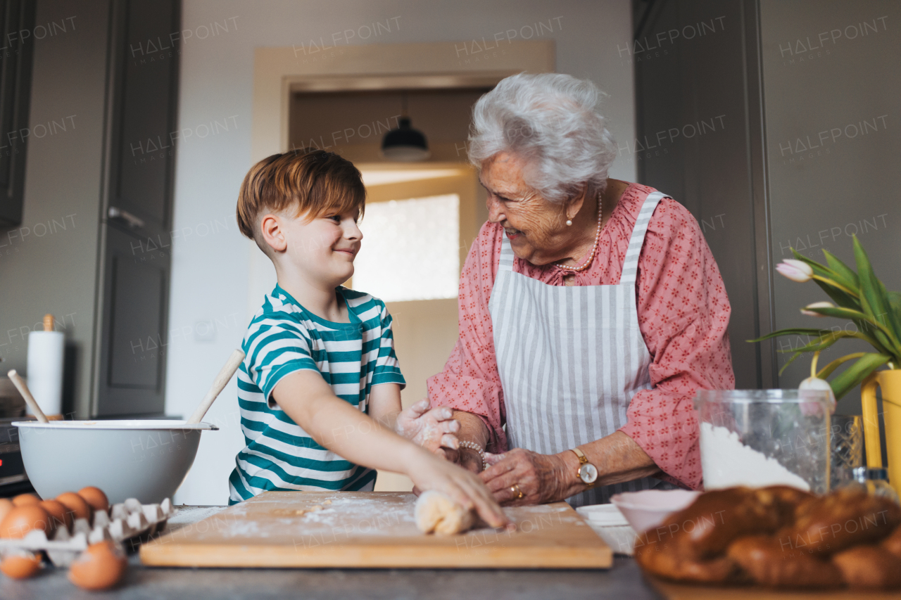 Grandmother with grandson preparing traditional easter meals, kneading dough for easter cross buns. Passing down family recipes, custom and stories. Concept of family easter holidays.