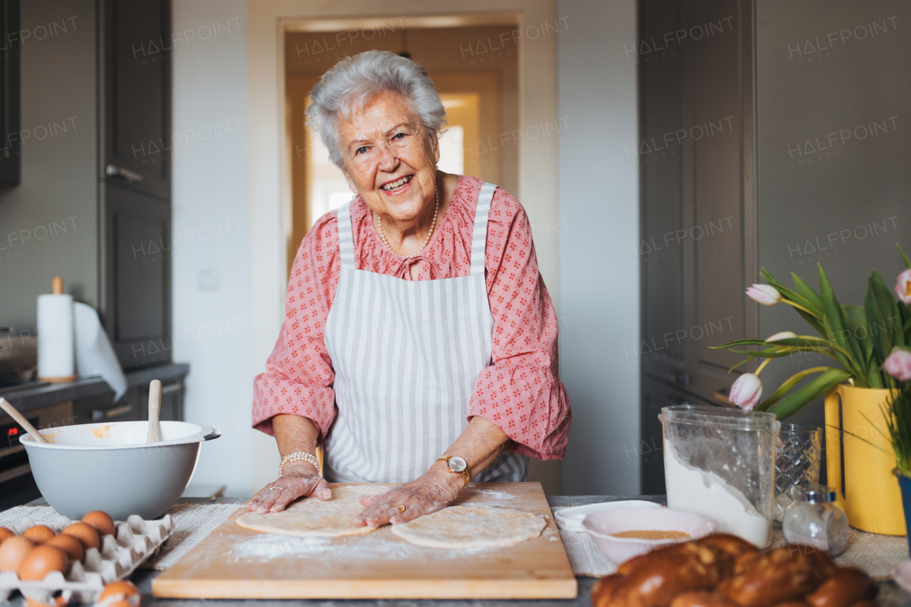 Senior woman preparing traditional easter meals for family, kneading dough for easter cross buns. Recreating family recipes, custom. Concept of easter holidays and traditions.