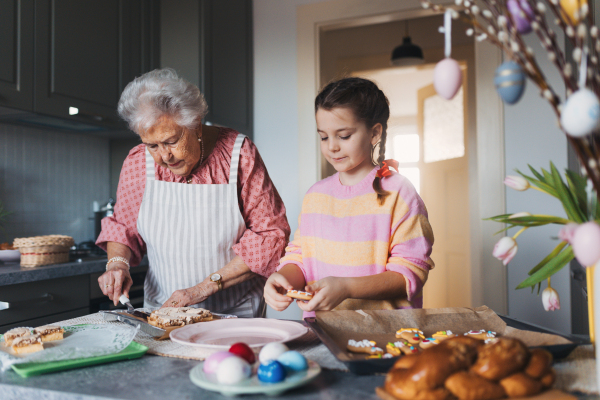 Grandmother with grandaughter preparing traditional easter meals, baking cakes and sweets. Passing down family recipes, custom and stories. Concept of family easter holidays.