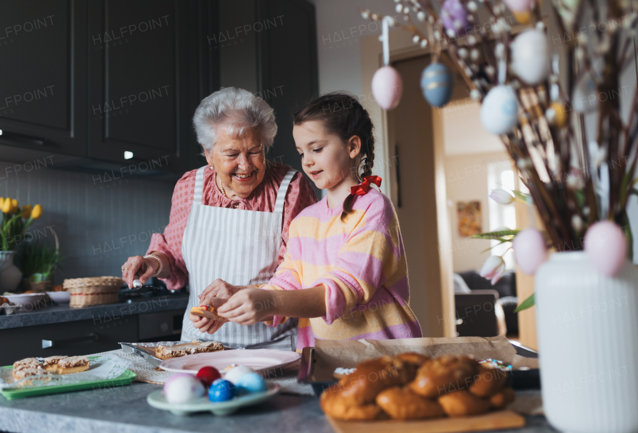 Grandmother with grandaughter preparing traditional easter meals, baking cakes and sweets. Passing down family recipes, custom and stories. Concept of family easter holidays.