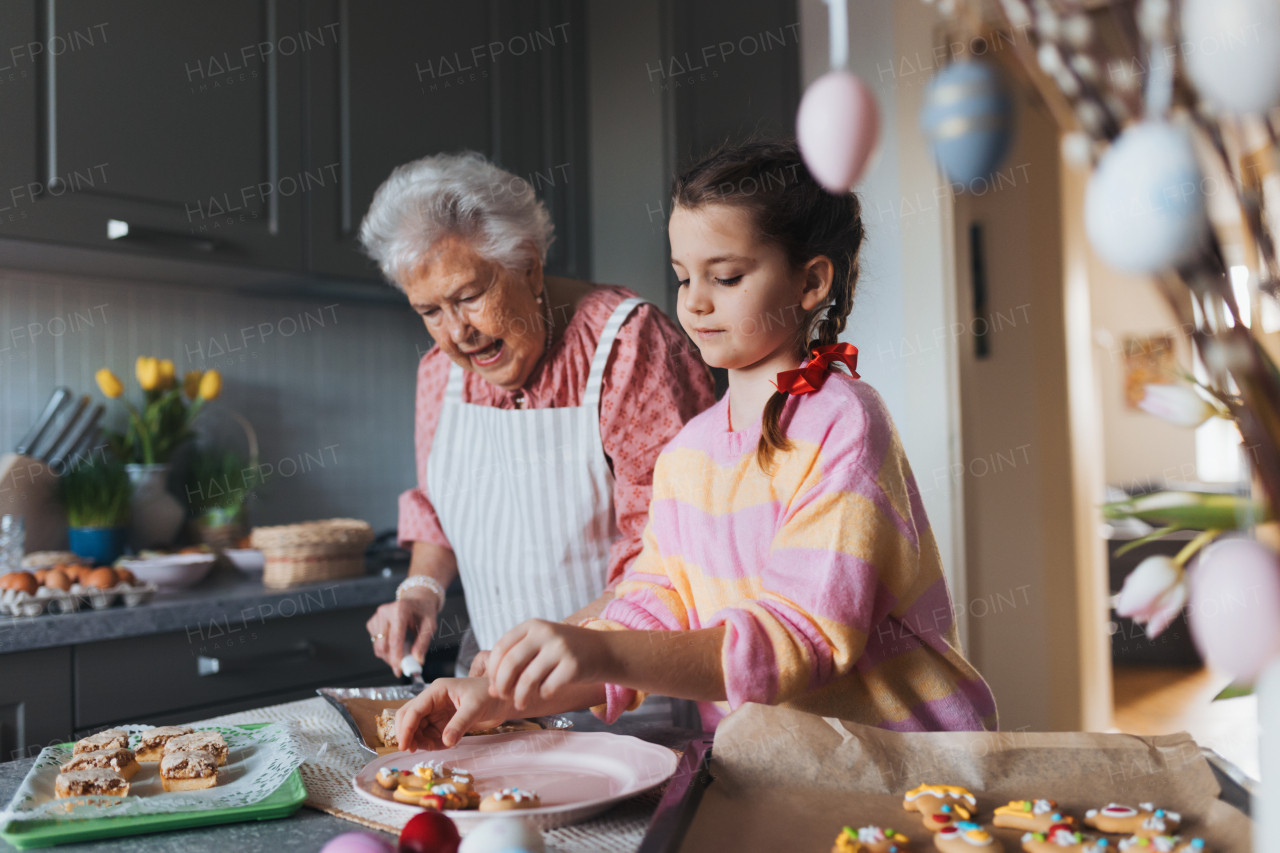 Grandmother with granddaughter preparing traditional easter meals, baking cakes and sweets. Passing down family recipes, custom and stories. Concept of family easter holidays.