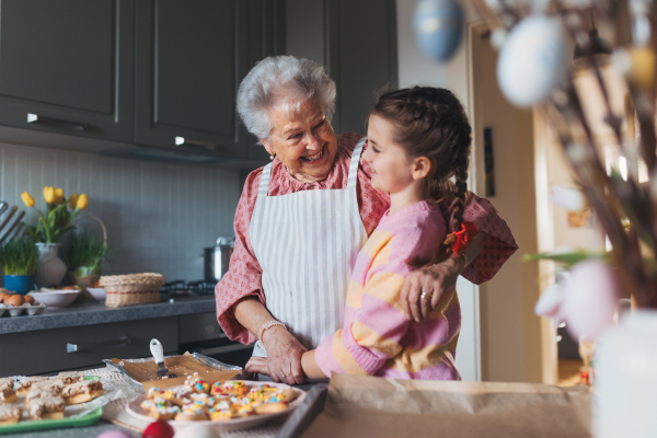 Grandmother with grandaughter preparing traditional easter meals, baking cakes and sweets. Passing down family recipes, custom and stories. Concept of family easter holidays.