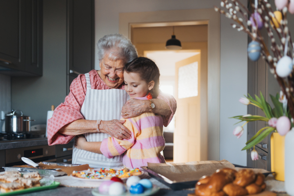 Grandmother with granddaughter preparing traditional easter meals, baking cakes and sweets. Passing down family recipes, custom and stories. Concept of family easter holidays.