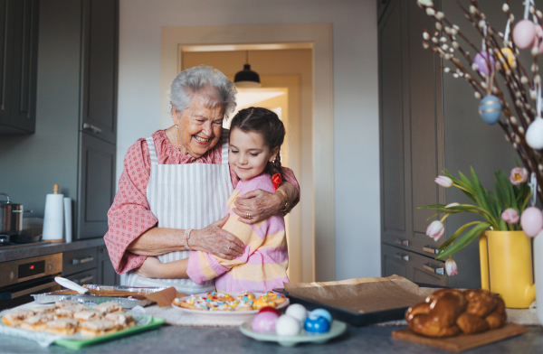 Grandmother with grandaughter preparing traditional easter meals, baking cakes and sweets. Passing down family recipes, custom and stories. Concept of family easter holidays.