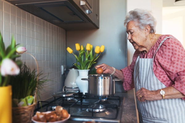 Senior woman preparing traditional easter meals for family, boiling eggs. Recreating family traditions and customs. Concept of easter holidays and traditions.