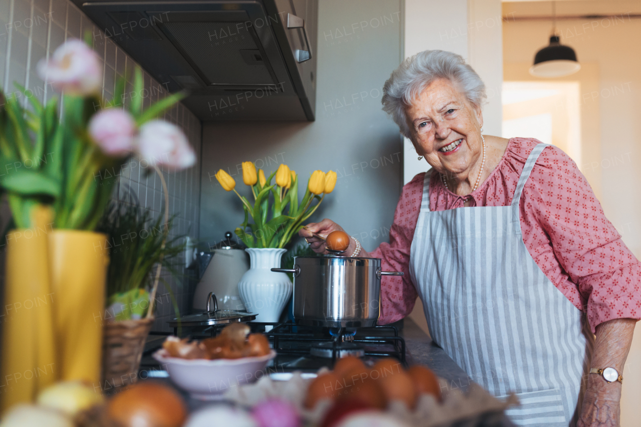 Senior woman preparing traditional easter meals for family, boiling eggs. Recreating family traditions and customs. Concept of easter holidays and traditions.