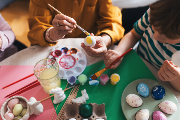 Close up of decorating easter eggs at home. Tradition of painting eggs with brush and easter egg dye. Concept of family easter holidays.