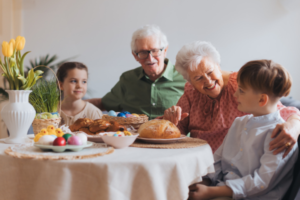 Grandparetns with grandchildren eating traditional easter lunch. Recreating family traditions and customs. Concept of family easter holidays.