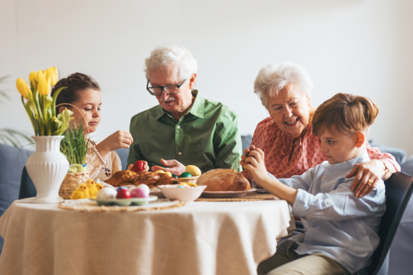 Grandparetns with grandchildren eating traditional easter lunch. Recreating family traditions and customs. Concept of family easter holidays.