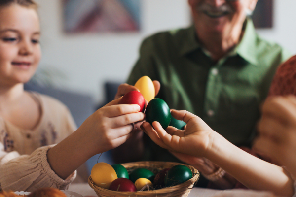 Grandparents and girl holding decorated easter eggs. Tradition of painting eggs with brush and easter egg dye. Concept of family easter holidays.