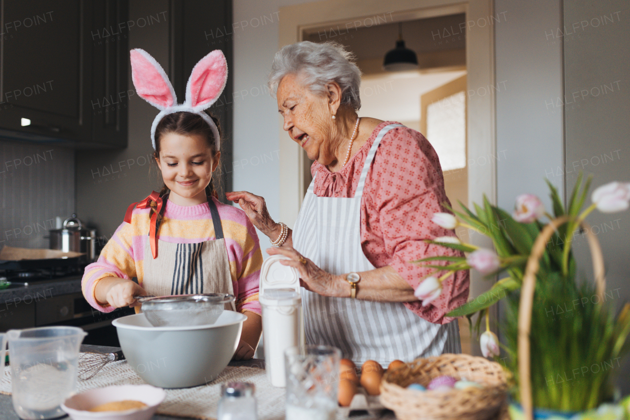 Grandmother with grandaughter preparing traditional easter meals, baking cakes and sweets. Passing down family recipes, custom and stories. Concept of family easter holidays.