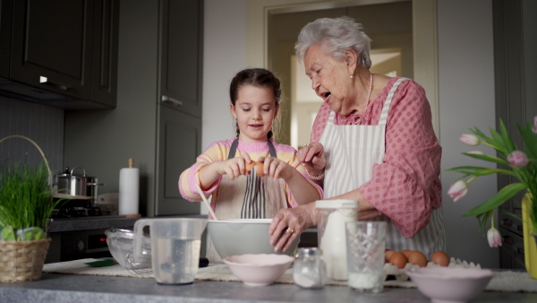 Grandmother with grandaughter preparing traditional easter meals, baking cakes and sweets. Passing down family recipes, custom and stories. Concept of family easter holidays.