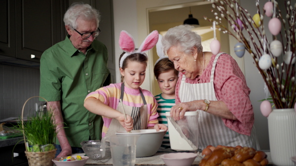 Grandparents with grandchildren preparing traditional easter meals, baking cakes and sweets. Passing down family recipes, custom and stories. Concept of family easter holidays.