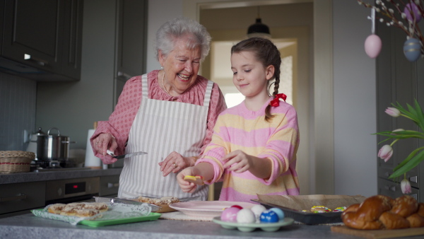 Grandmother with grandaughter preparing traditional easter meals, baking cakes and sweets. Passing down family recipes, custom and stories. Concept of family easter holidays.