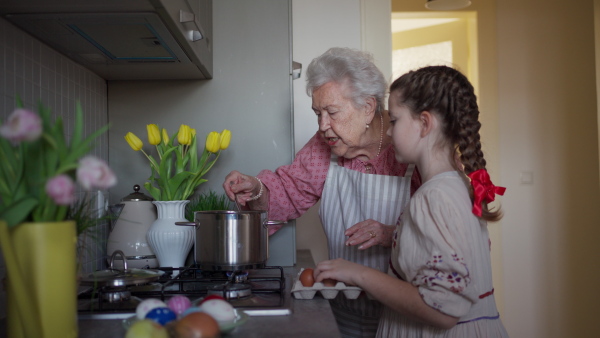 Grandmother with grandaughter preparing traditional easter meals, boiling eggs. Passing down family recipes, custom and stories. Concept of family easter holidays.