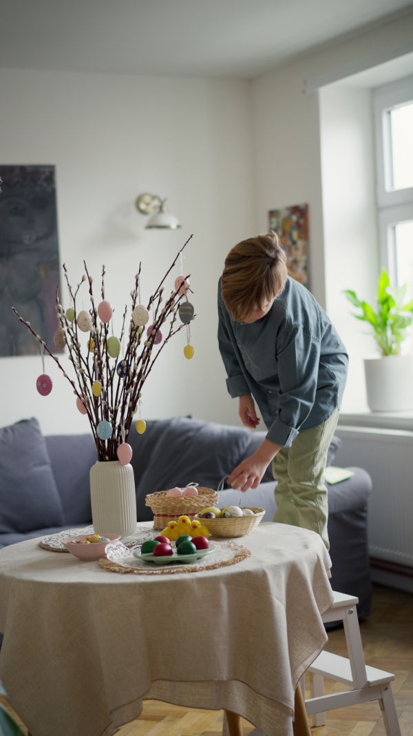 A little boy setting table for traditional easter lunch. Recreating family traditions and customs.