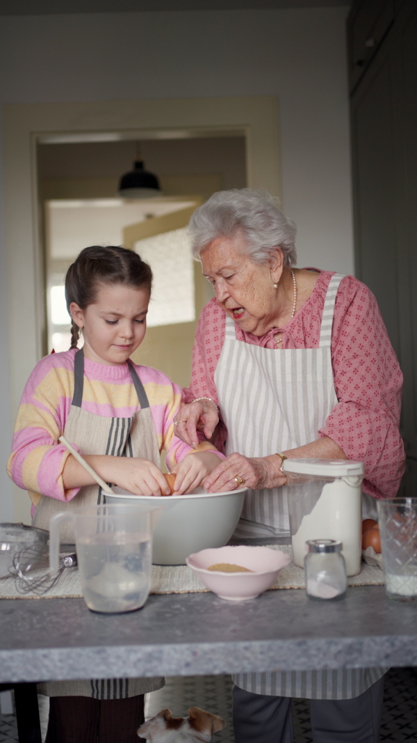 Grandmother with grandaughter preparing traditional easter meals, baking cakes and sweets. Passing down family recipes, custom and stories. Concept of family easter holidays.