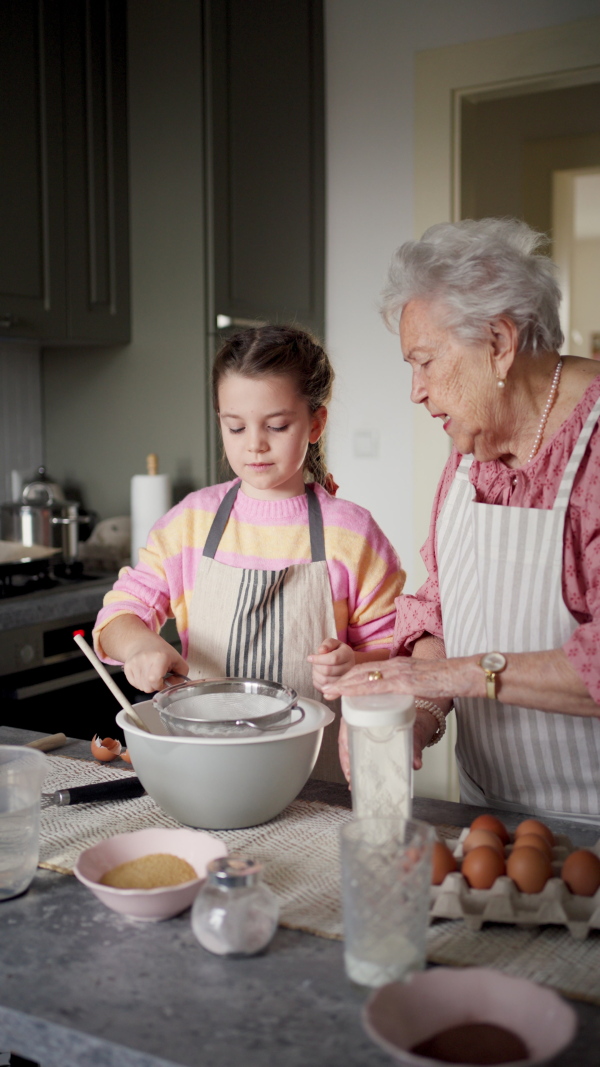 Grandmother with grandaughter preparing traditional easter meals, baking cakes and sweets. Passing down family recipes, custom and stories. Concept of family easter holidays.