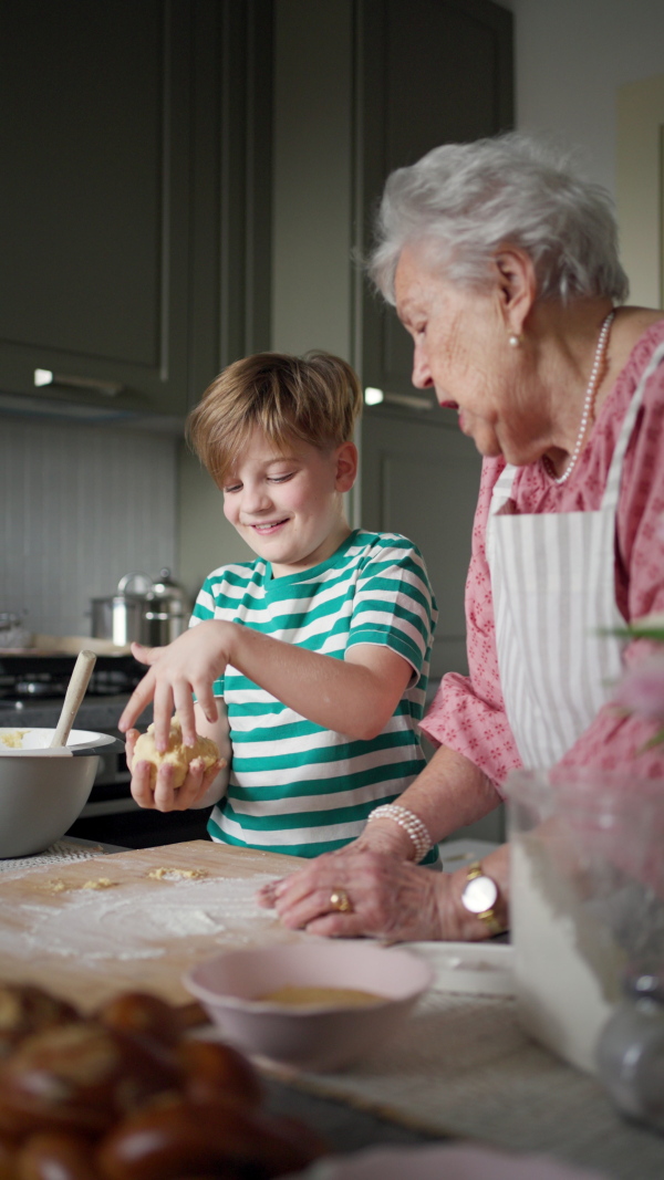 Grandmother with grandson preparing traditional easter meals, kneading dough for easter cross buns. Passing down family recipes, custom and stories. Concept of family easter holidays.