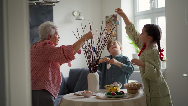 Grandmother with grandchildren setting table for traditional easter lunch. Recreating family traditions and customs. Concept of family easter holidays. Standing by table, praying.