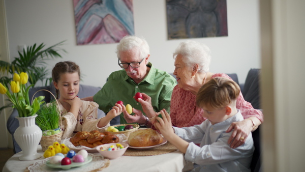 Grandparetns with grandchildren eating traditional easter lunch. Recreating family traditions and customs. Concept of family easter holidays.